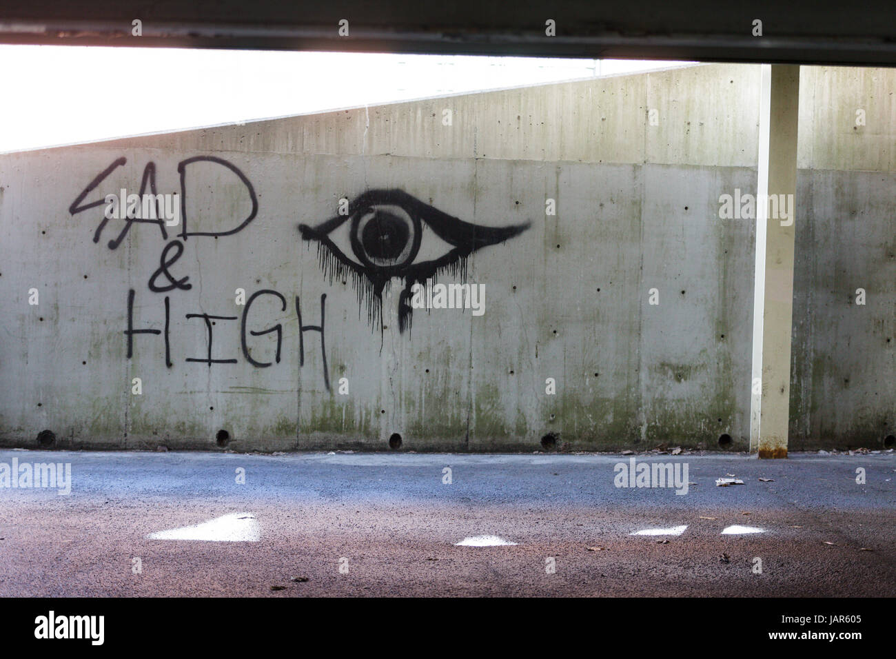 TROY, NEW YORK, FEBRUARY 25, 2017: Graffiti on wall of a parking lot 'Sad and High' may be expression of the opiate addiction sweeping USA. Stock Photo