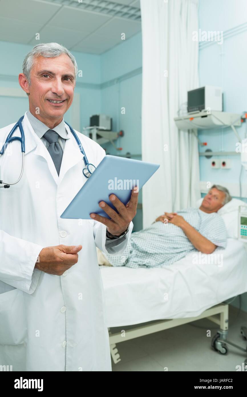 Happy doctor with a tactile tablet while standing Stock Photo
