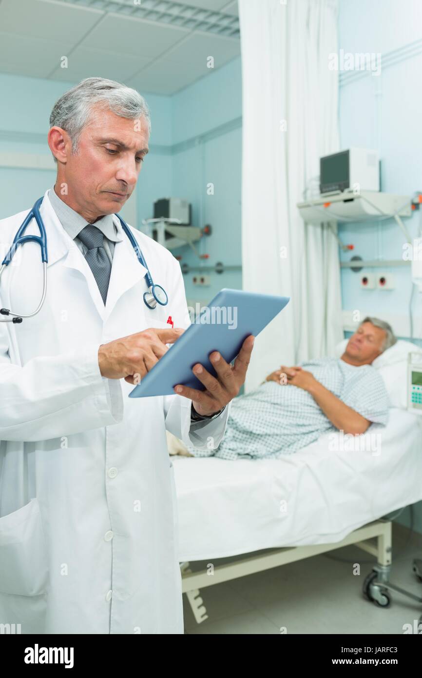 Doctor using a tactile tablet while standing Stock Photo