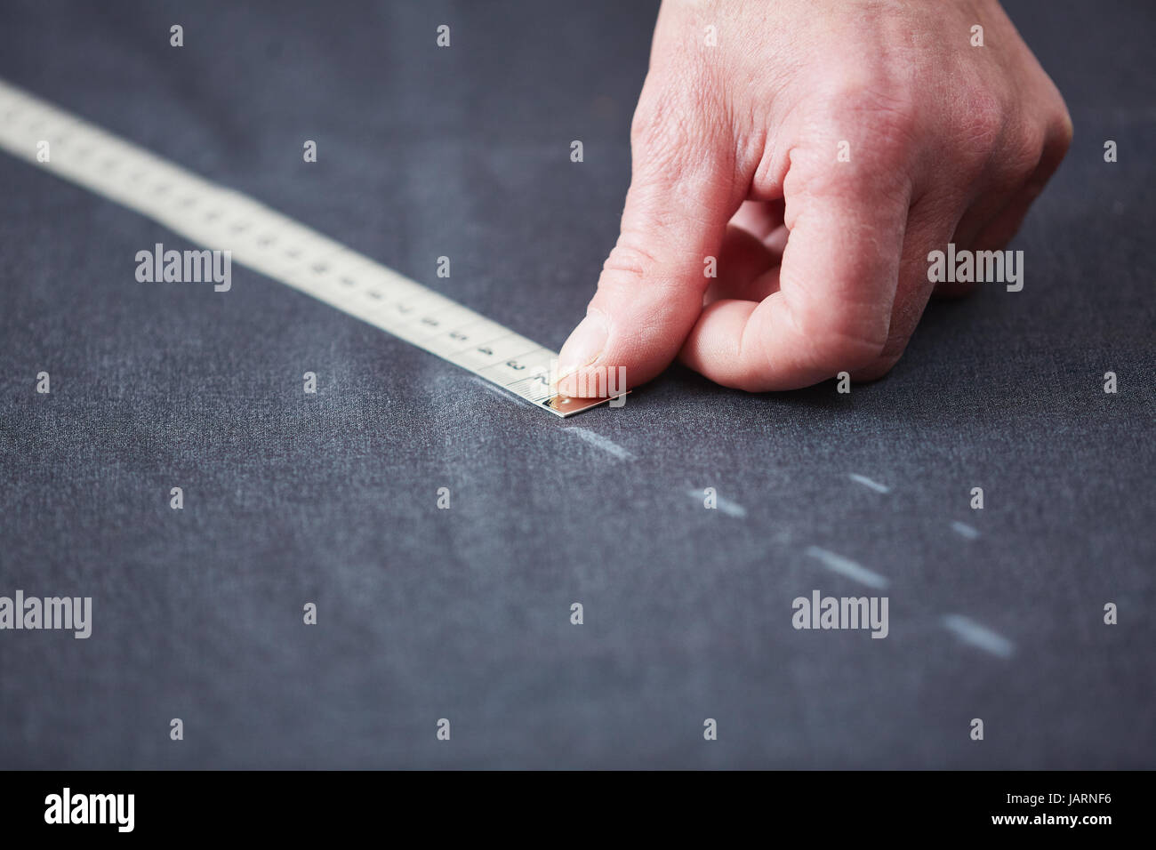 Tailors Hand Measuring Fabric on Table Stock Photo