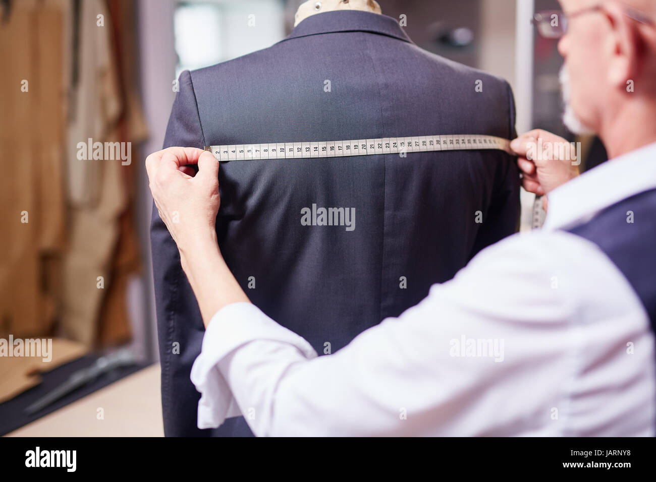 Tailor Measuring Garment in Atelier Stock Photo