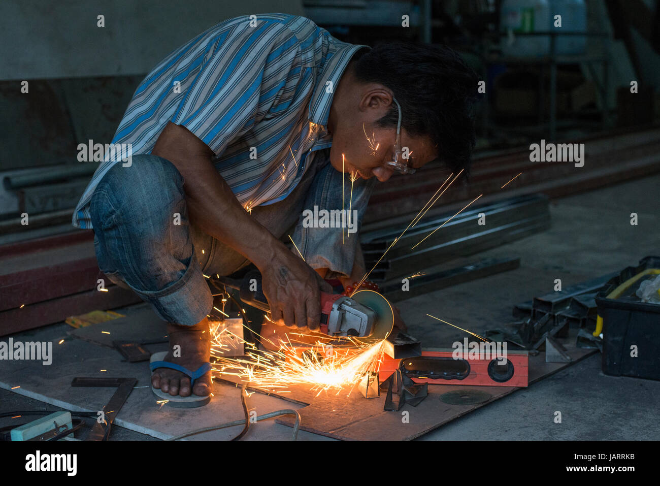 An Industrial worker uses an angle grinder at his place of work at Hpa-an, Myanmar (Burma) Stock Photo