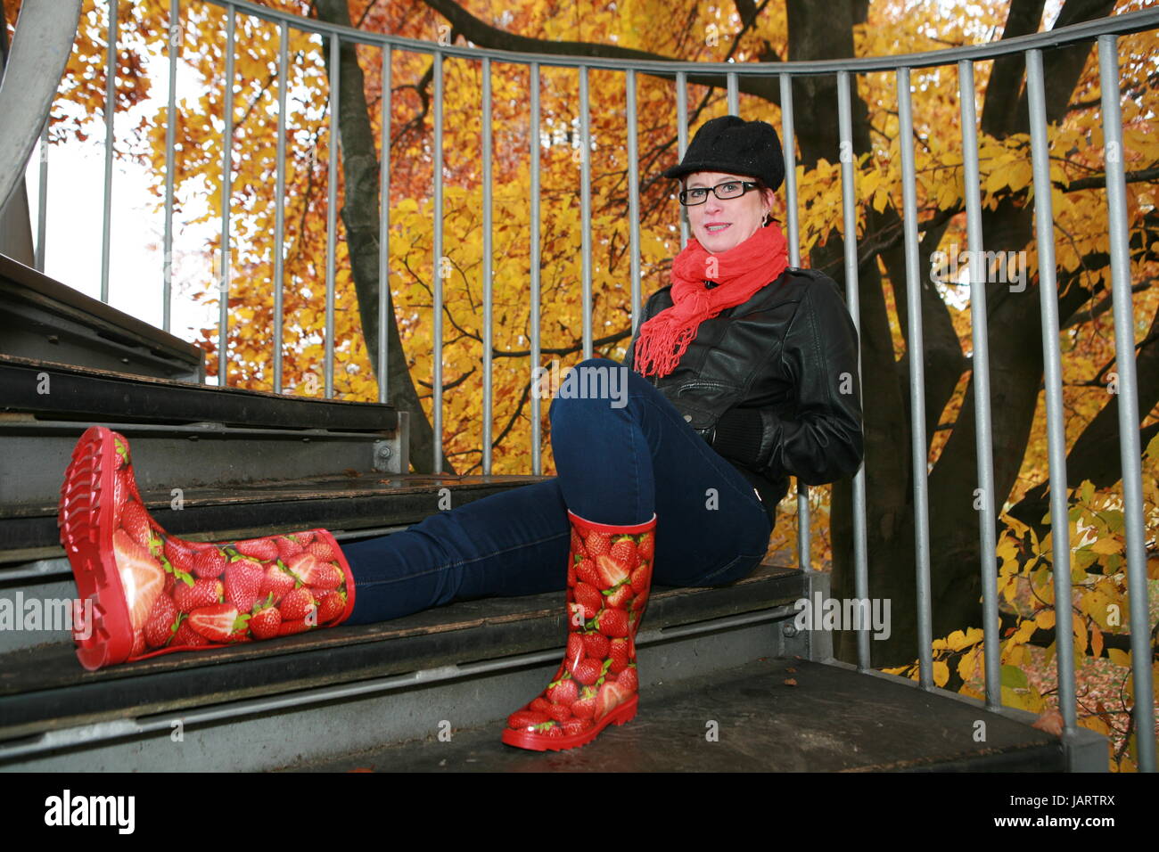 Frau um die 50 mit Gummistiefeln, auf einer Treppe sitzend, mit roten  Gummistiefeln Stock Photo - Alamy