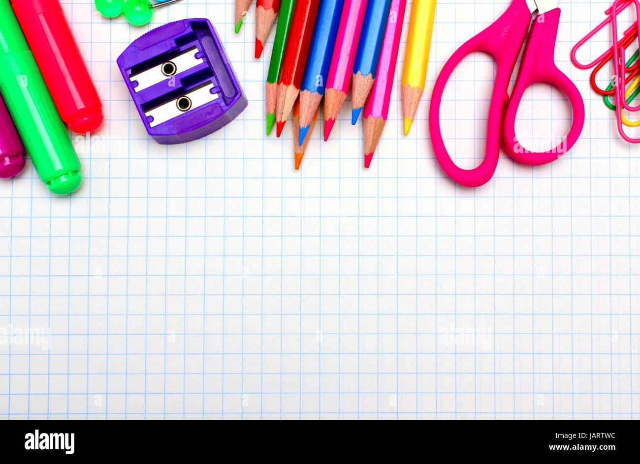 Colorful school supplies top border over a graphing paper background Stock Photo