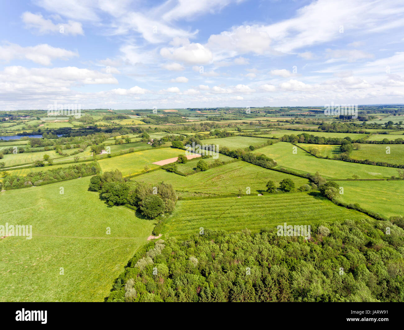 Aerial view of rural english countryside of green farm fields, wildflower meadows, hedgerow, woods, on a summer day . Stock Photo
