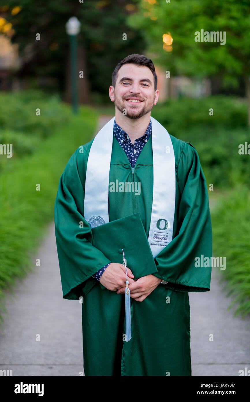 EUGENE, OR - MAY 23, 2017: Male college student with cap and gown poses for a graduation photo on campus at the University of Oregon in Eugene. Stock Photo