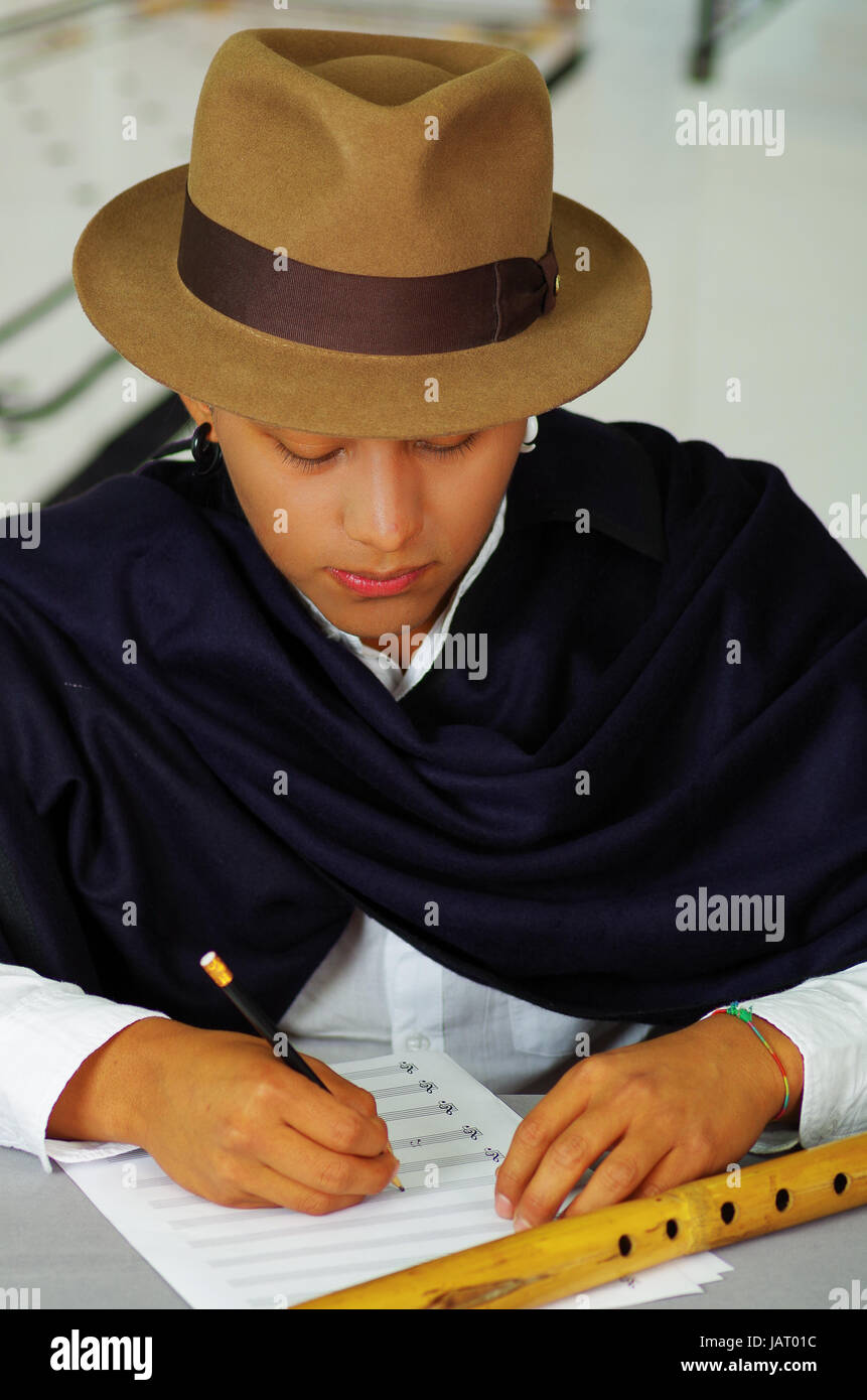 Indigenous young latin man writing notes to music with quena flute ...