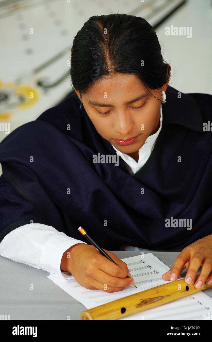 Indigenous young latin man writing notes to music with quena flute ...