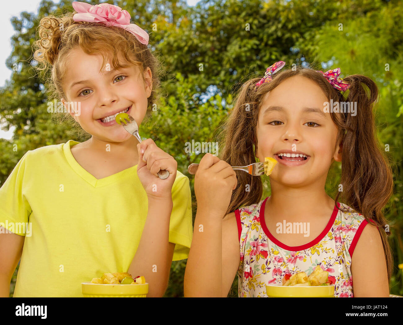 Two beautiful young girls, preparing to eat a healthy fruit salad using
