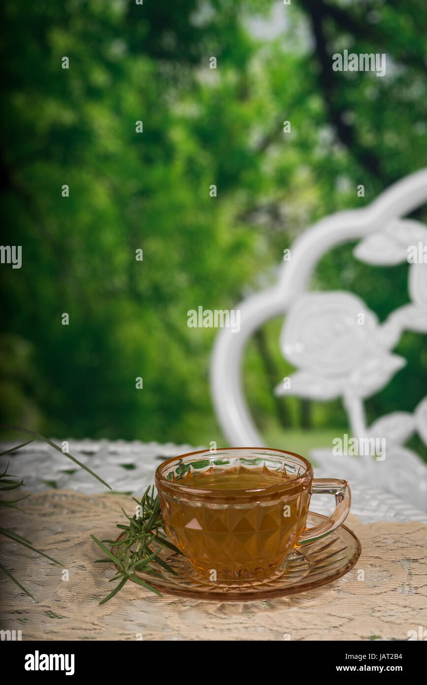 Glass cup of tea on a white table in an outdoor setting Stock Photo
