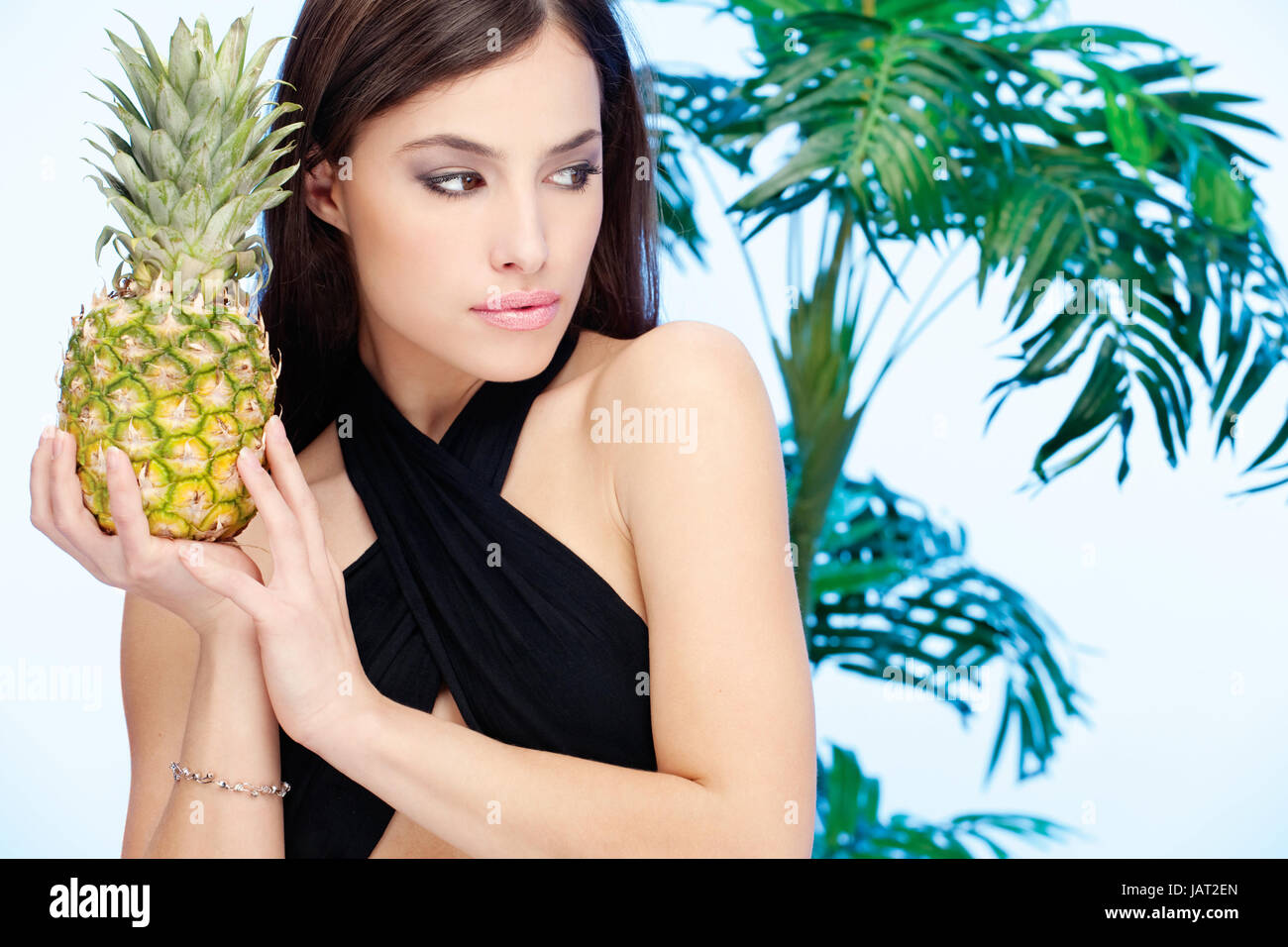 Woman holding pineapple in front of a palm tree Stock Photo Alamy