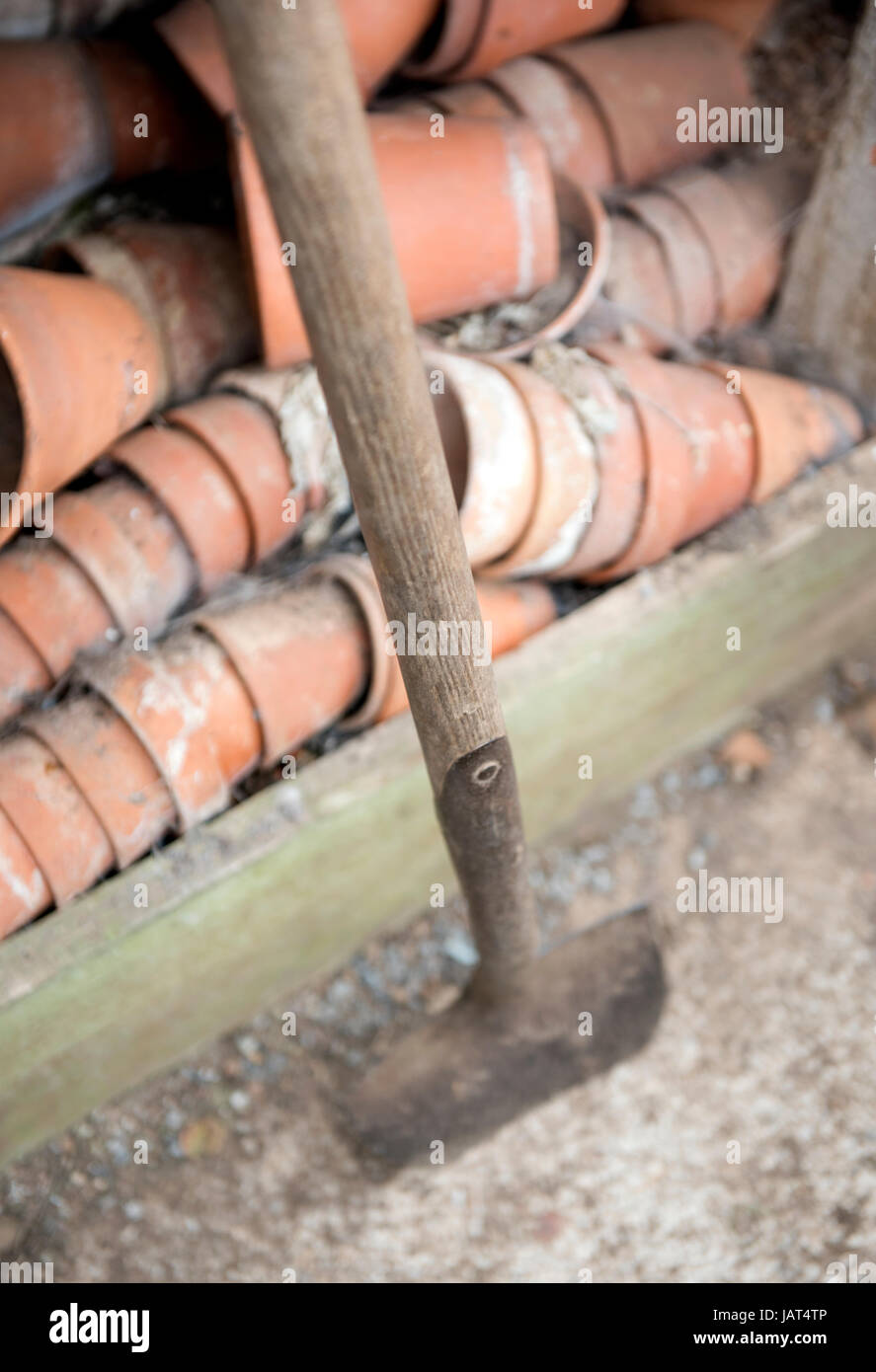 A traditional spade in a greenhouse with old fashioned clay pots Stock