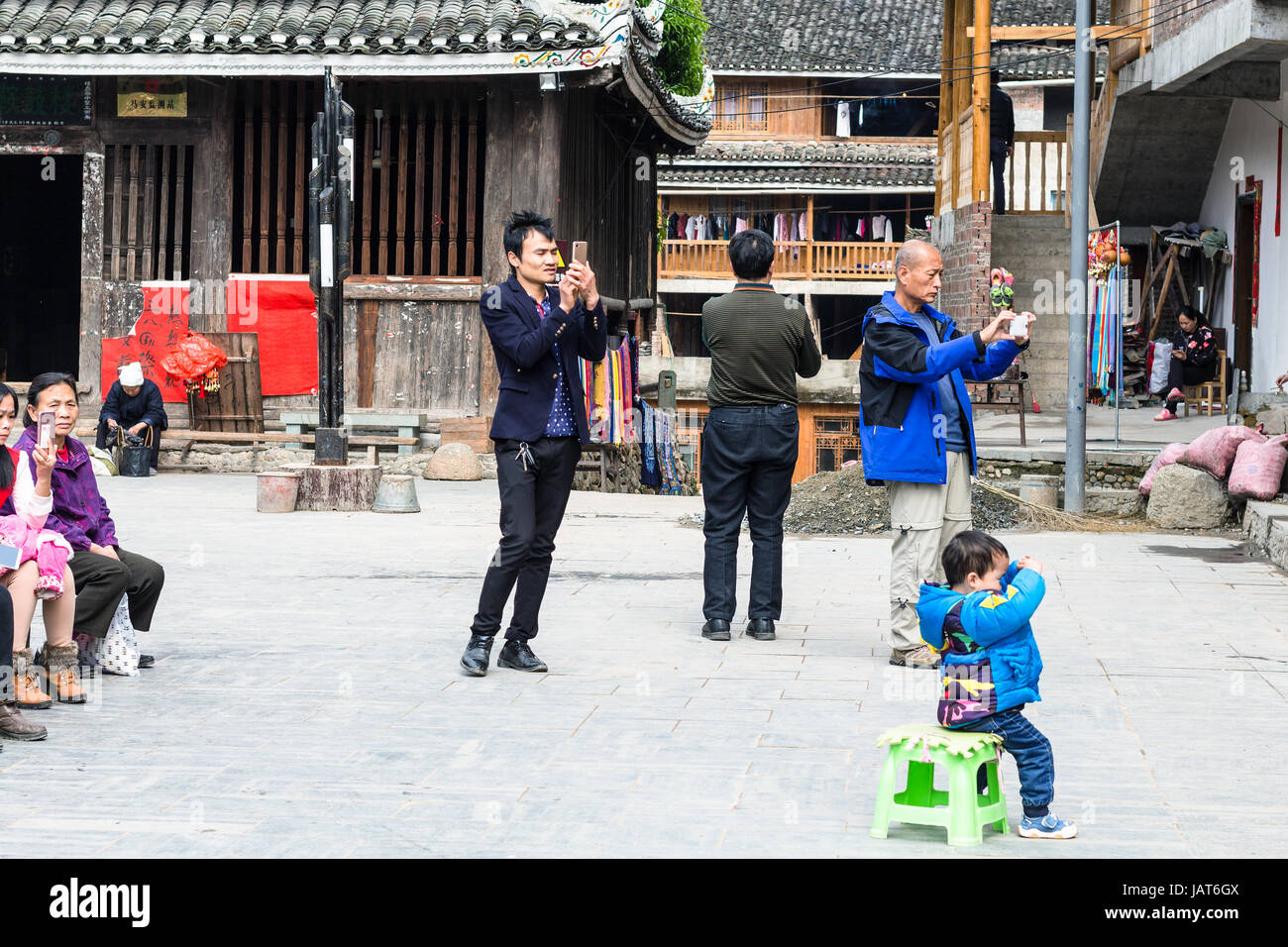 CHENGYANG, CHINA - MARCH 27, 2017: tourists take photos of Dong Culture Show on square of Folk Custom Centre in Chengyang village of Sanjiang County.  Stock Photo
