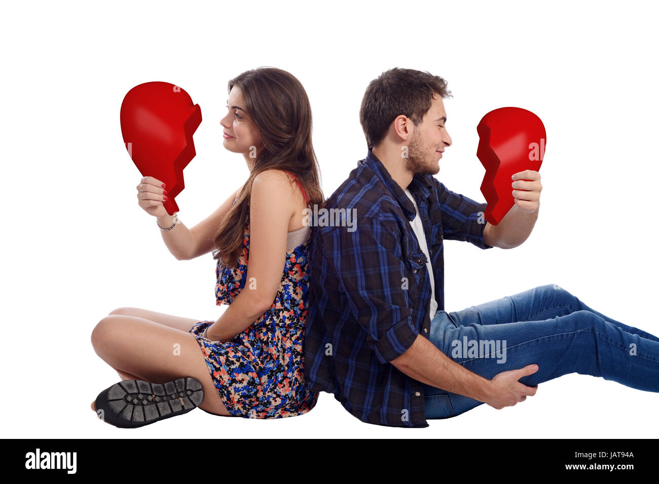 Portrait of a young couple holding two halves of broken heart. Isolated white background. Stock Photo