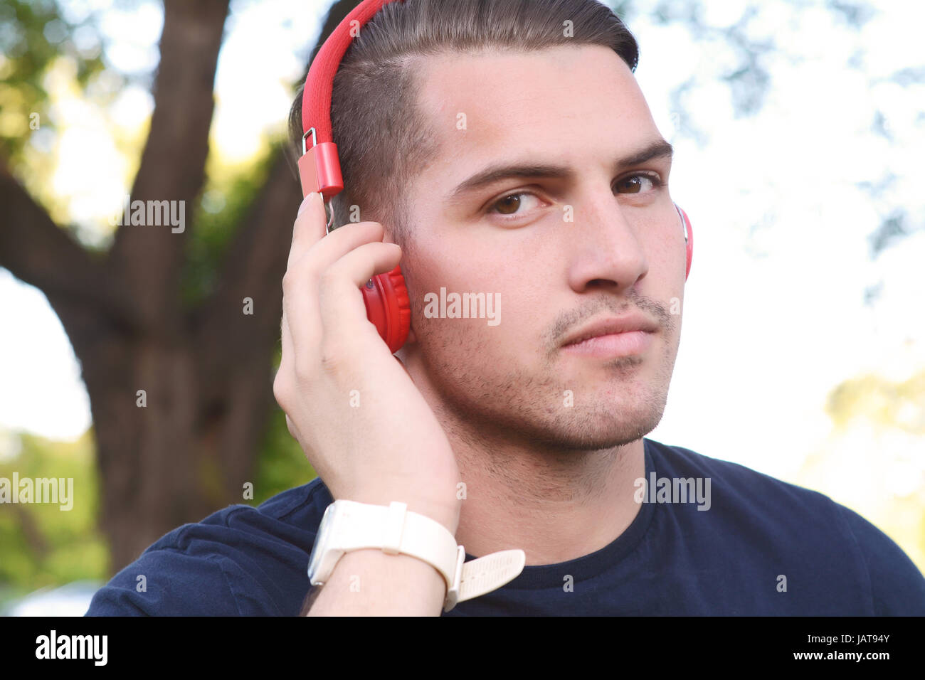 Close up of young handsome man with headphones in a park. Outdoors. Stock Photo