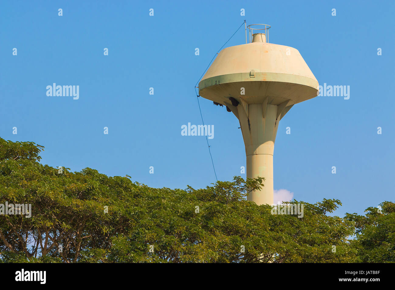 large outdoor champagne shape metal water tower, suuny day with deep clear blue sky and green trees foreground Stock Photo