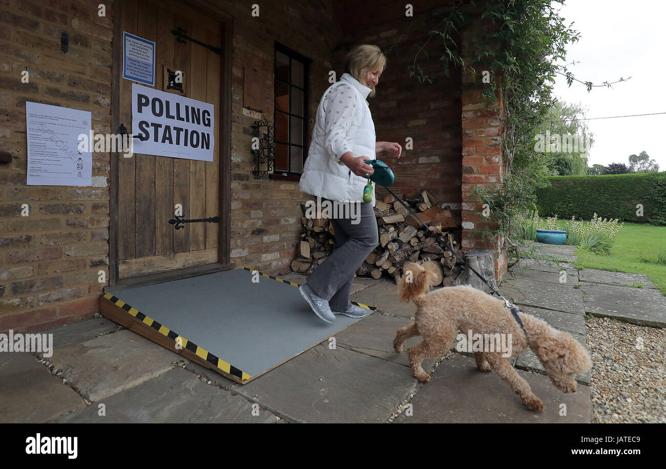 A voter with her dog leaves a polling station in a guest house annex in Dogmersfield, Hampshire, as voters head to the polls across the UK to vote in the General Election. Stock Photo