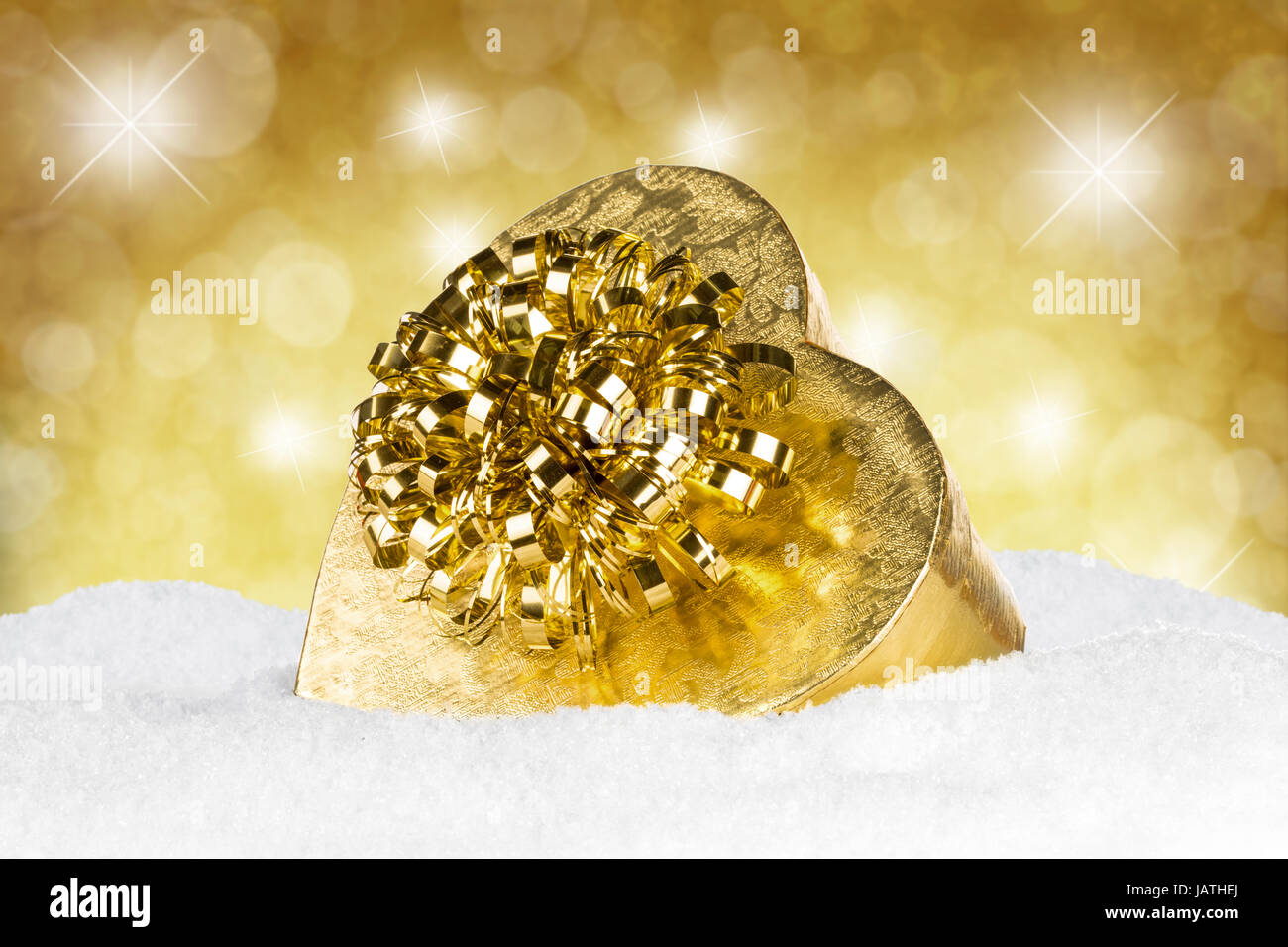 goldenes geschenk auf schnee vor goldenem hintergrung Stock Photo