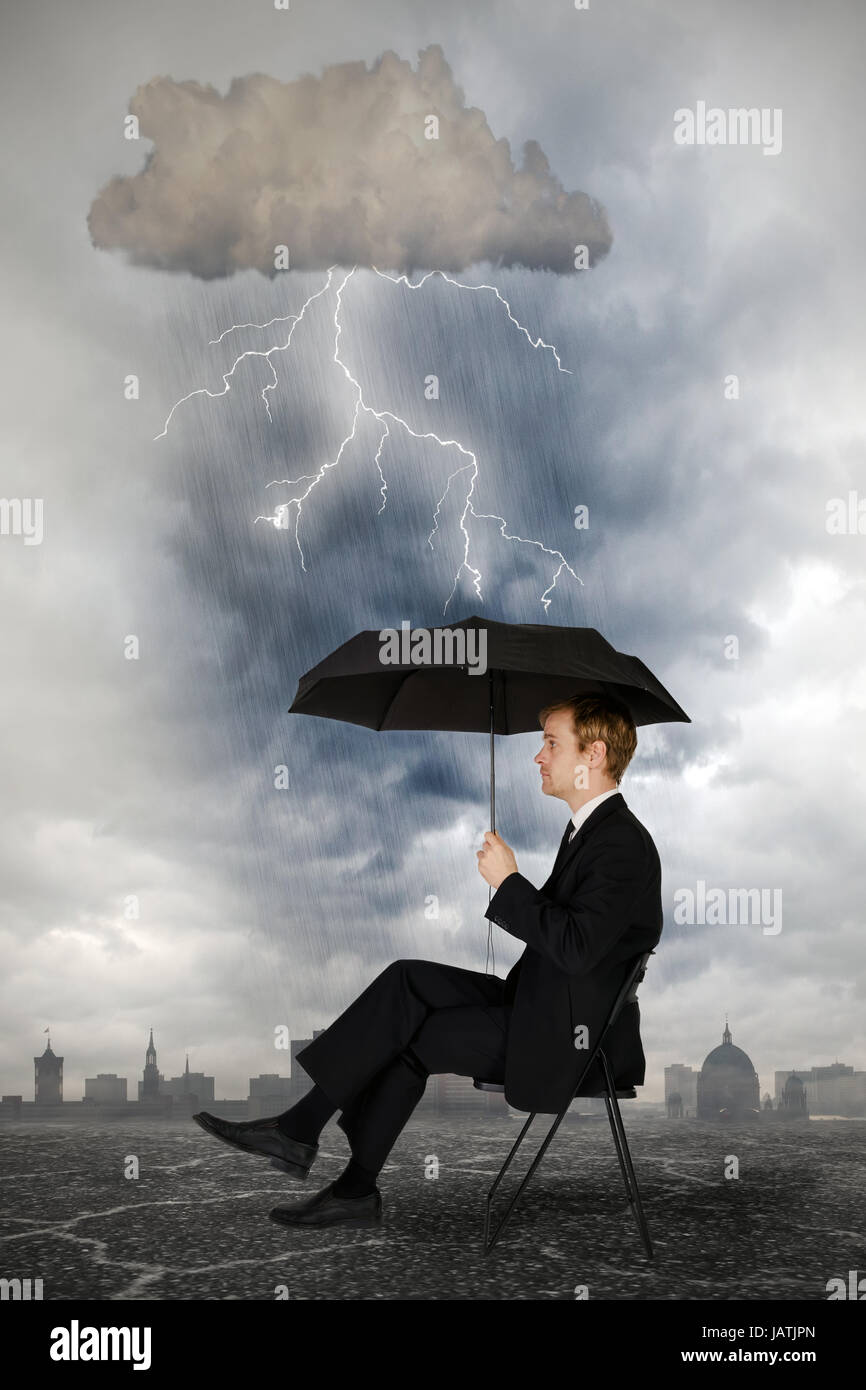 Businessmann sitzt mit einem Regenschirm unter einer Gewitterwolke mit Blitzen Stock Photo