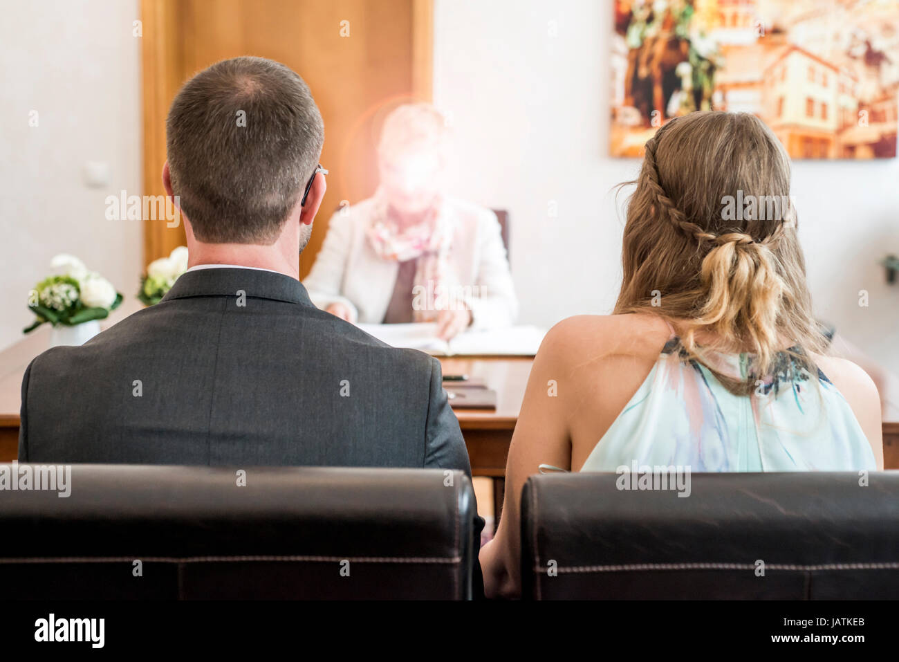 Young wedding couple bride and groom sitting together in front of the marriage registrar Stock Photo