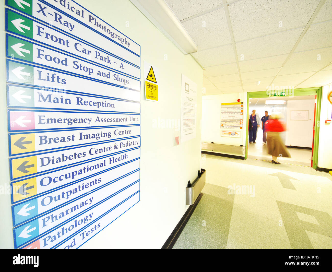 Signage in a UK hospital showing outpatient and treatment rooms with blurred movement of people in background Stock Photo