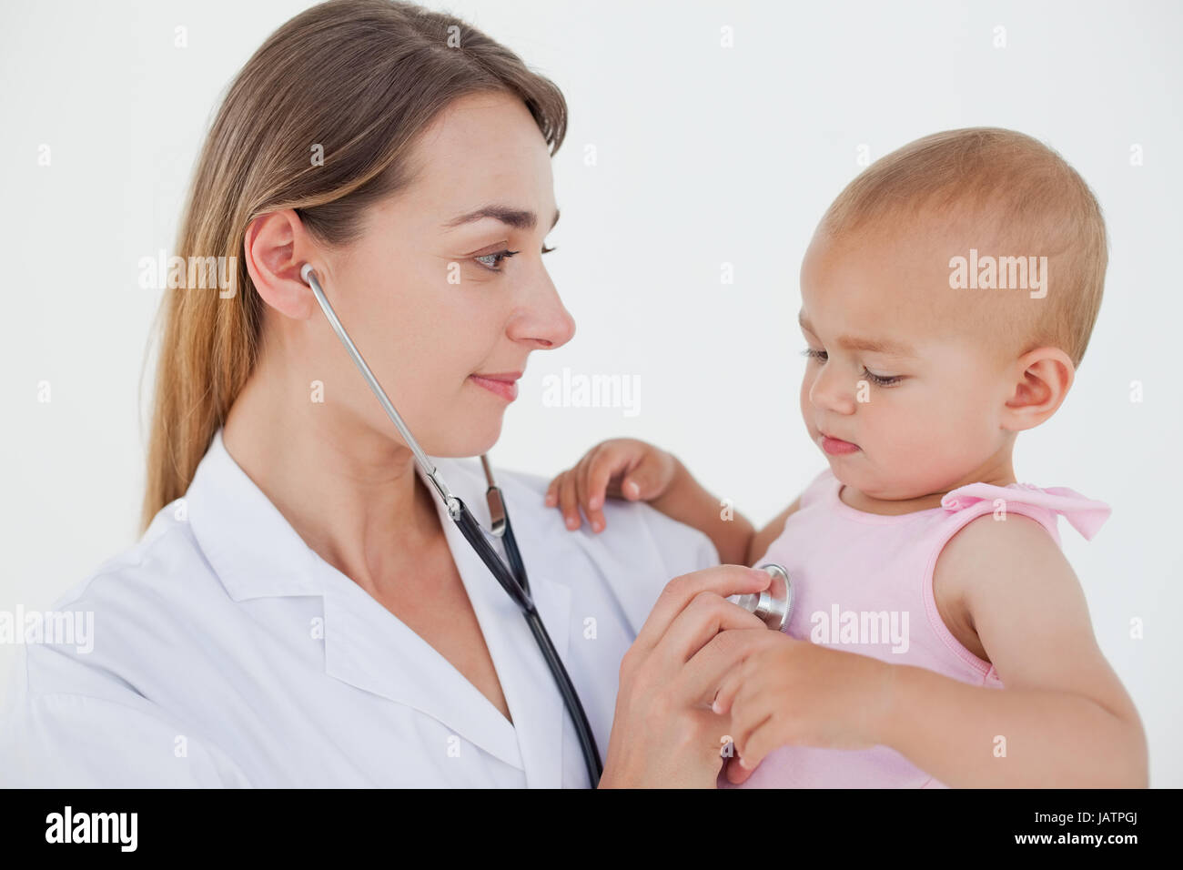 Doctor looking at the baby while auscultating her Stock Photo