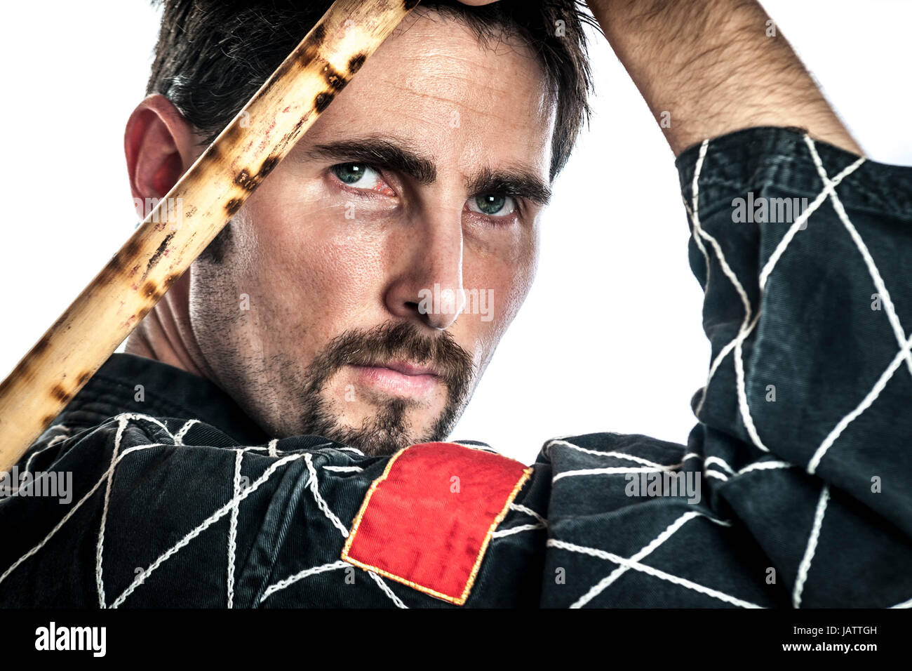 Martial arts master with black combat dress and two short bamboo sticks, isolated on white