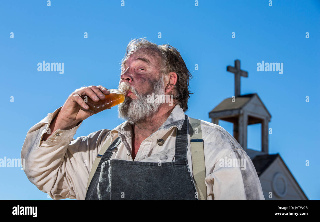 Old West Drunk Drinks a bottle of Liquor Stock Photo