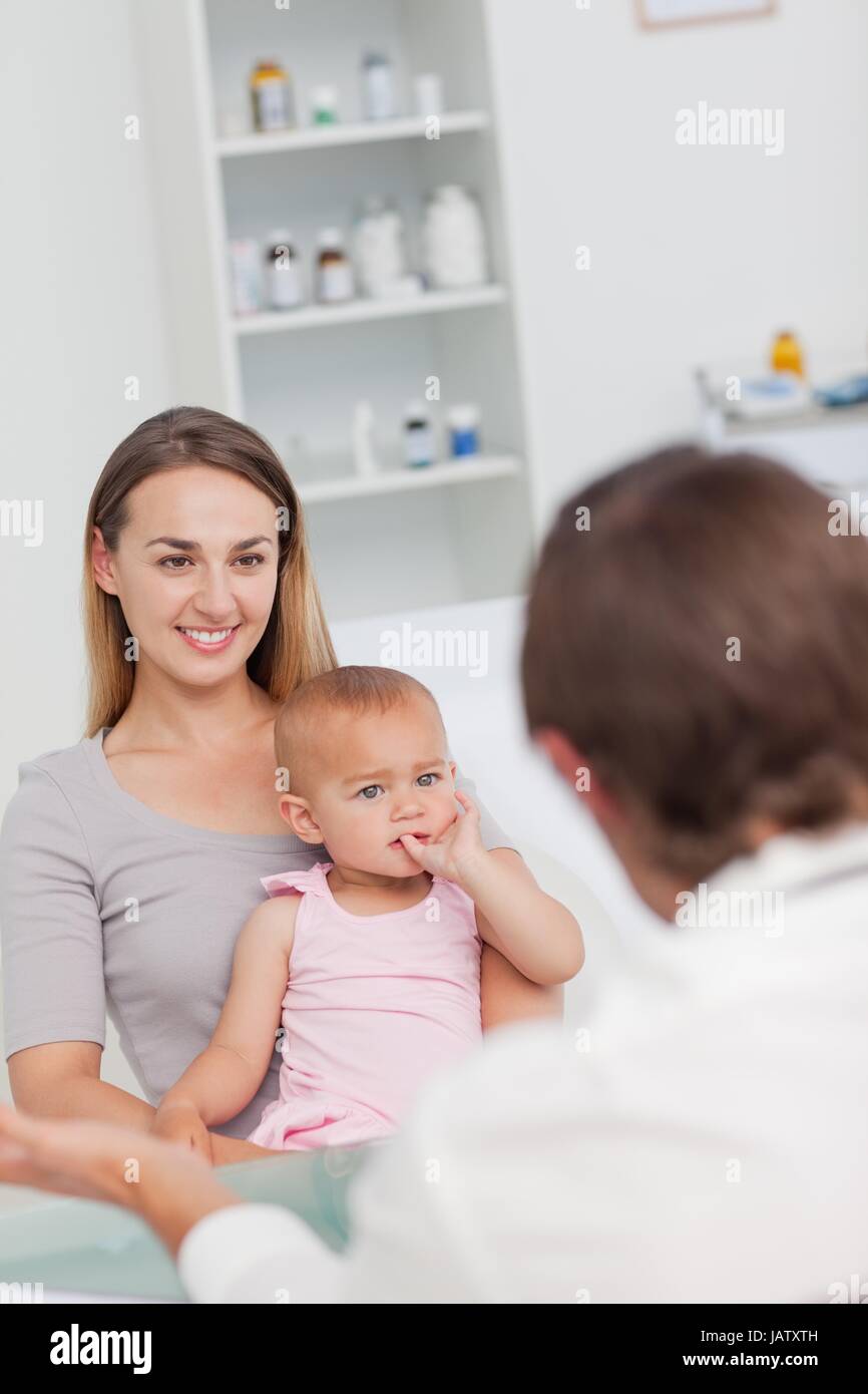 Little baby placing her fingers in her mouth while looking at the