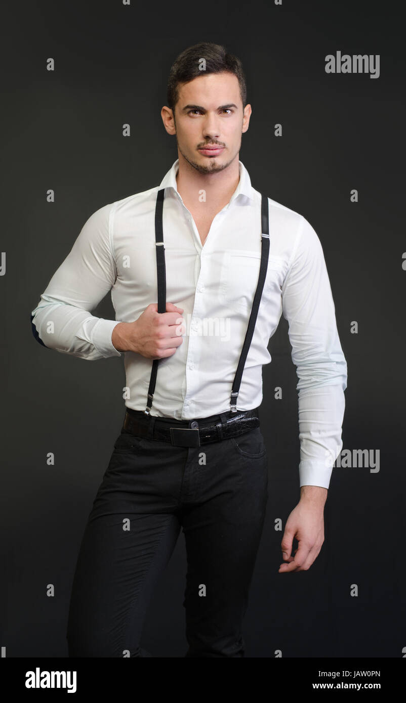 elegant-young-man-with-white-shirt-and-suspenders-on-dark-backgroung-JAW0PN.jpg