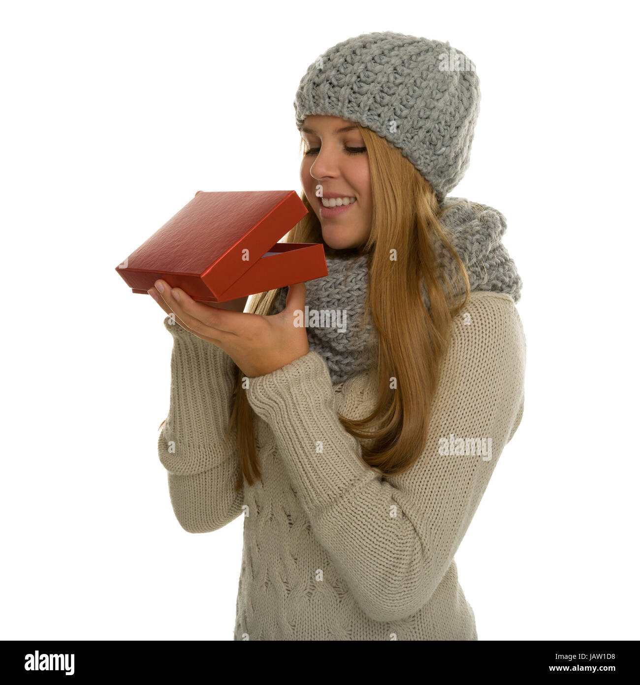 Junge Frau / Mädchen trägt Strickware und schaut erwartungsvoll in eine Geschenkverpackung. Vielleicht eine Überraschung zu Weihnachten oder ein Geschenk im neuen Jahr Stock Photo