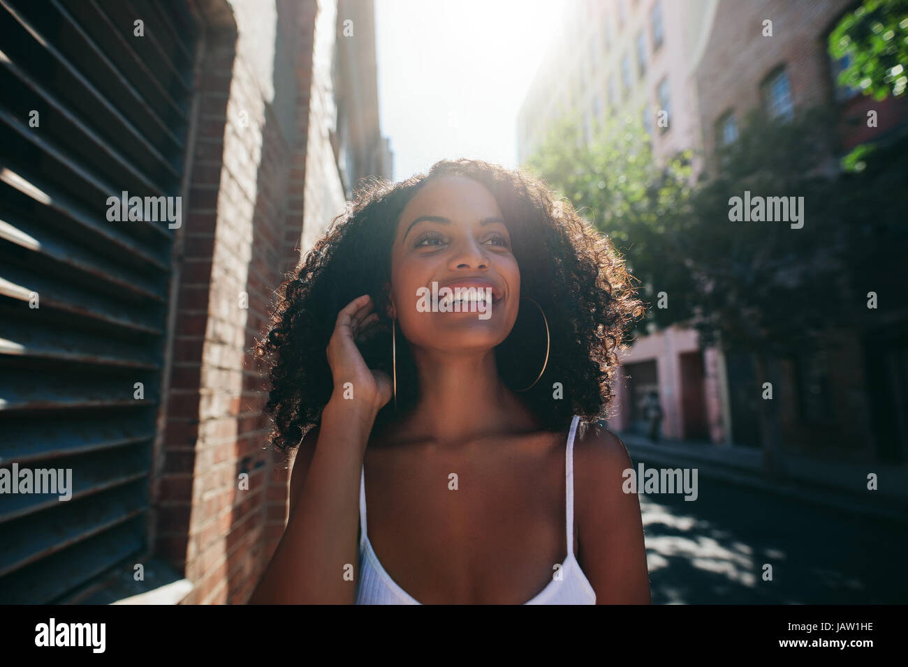 Portrait of beautiful young african woman walking down the city street ...