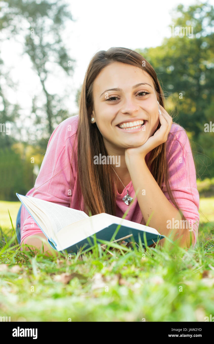 Happy student girl relaxing on green grass reading book Stock Photo - Alamy