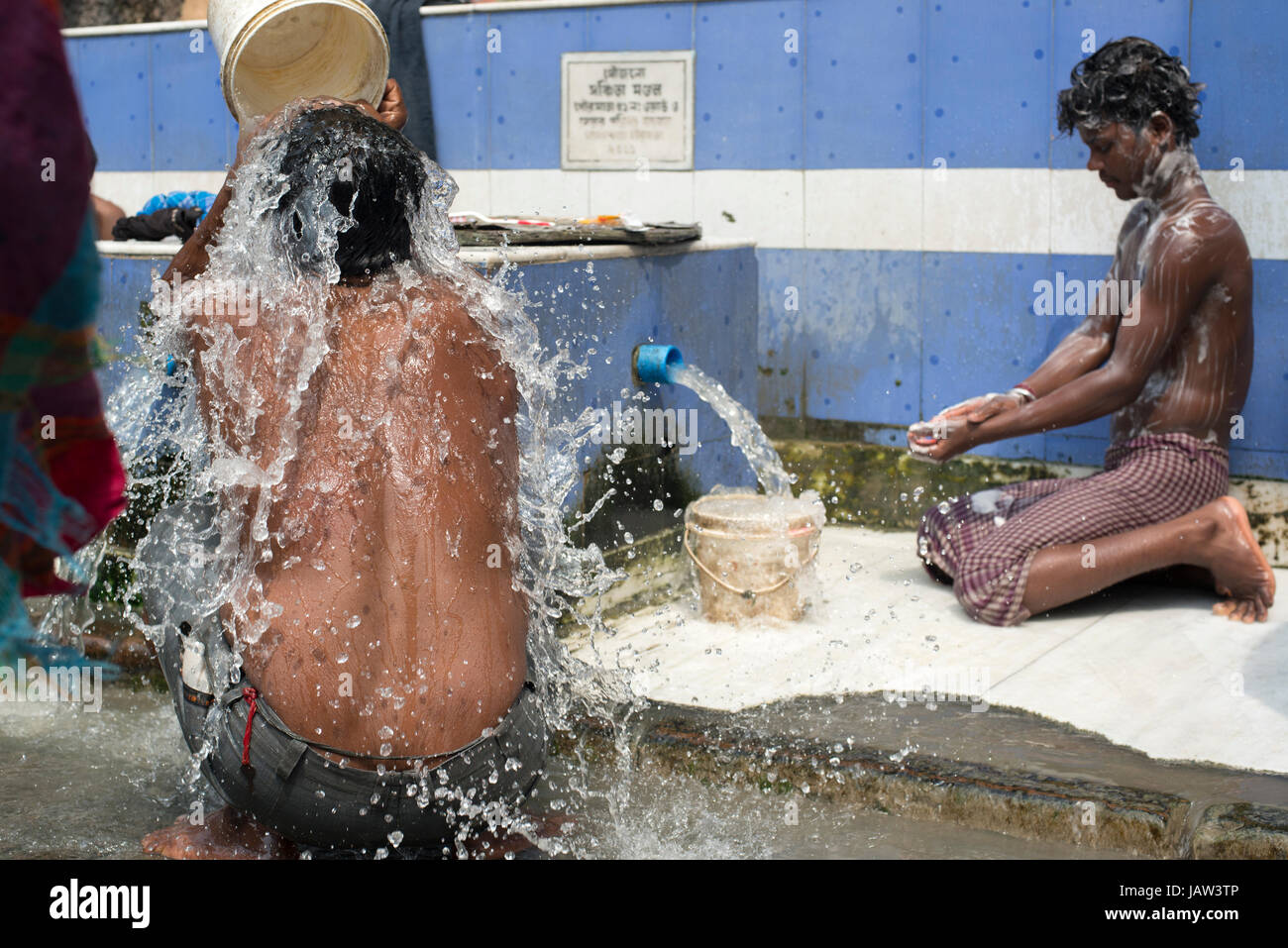 Two men bathe themselves at a roadside bathing place in Kolkata (Calcutta), West Bengal, India Stock Photo