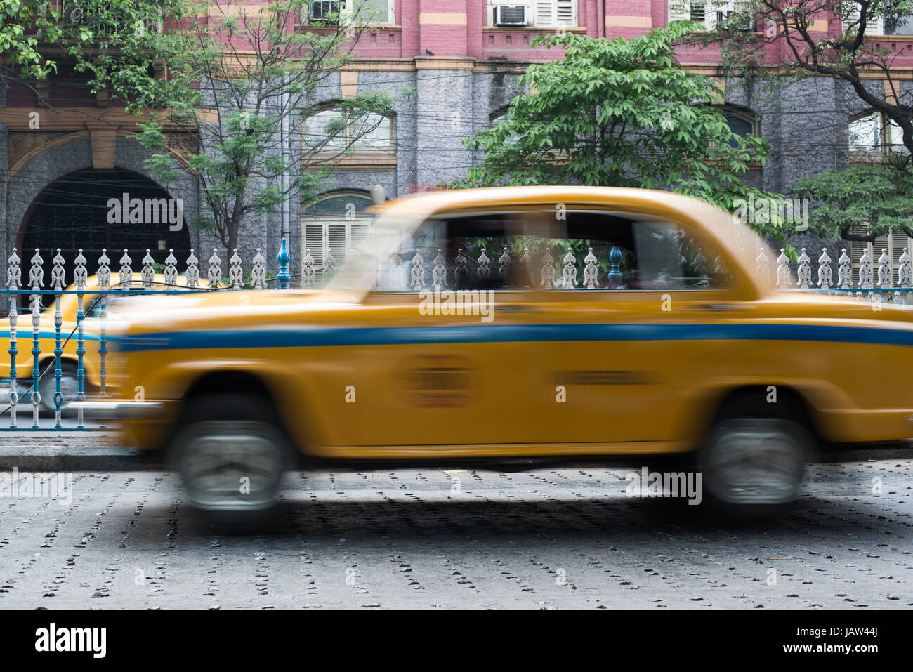 An iconic yellow taxi drives down a road in Kolkata (Calcutta), West Bengal, India Stock Photo