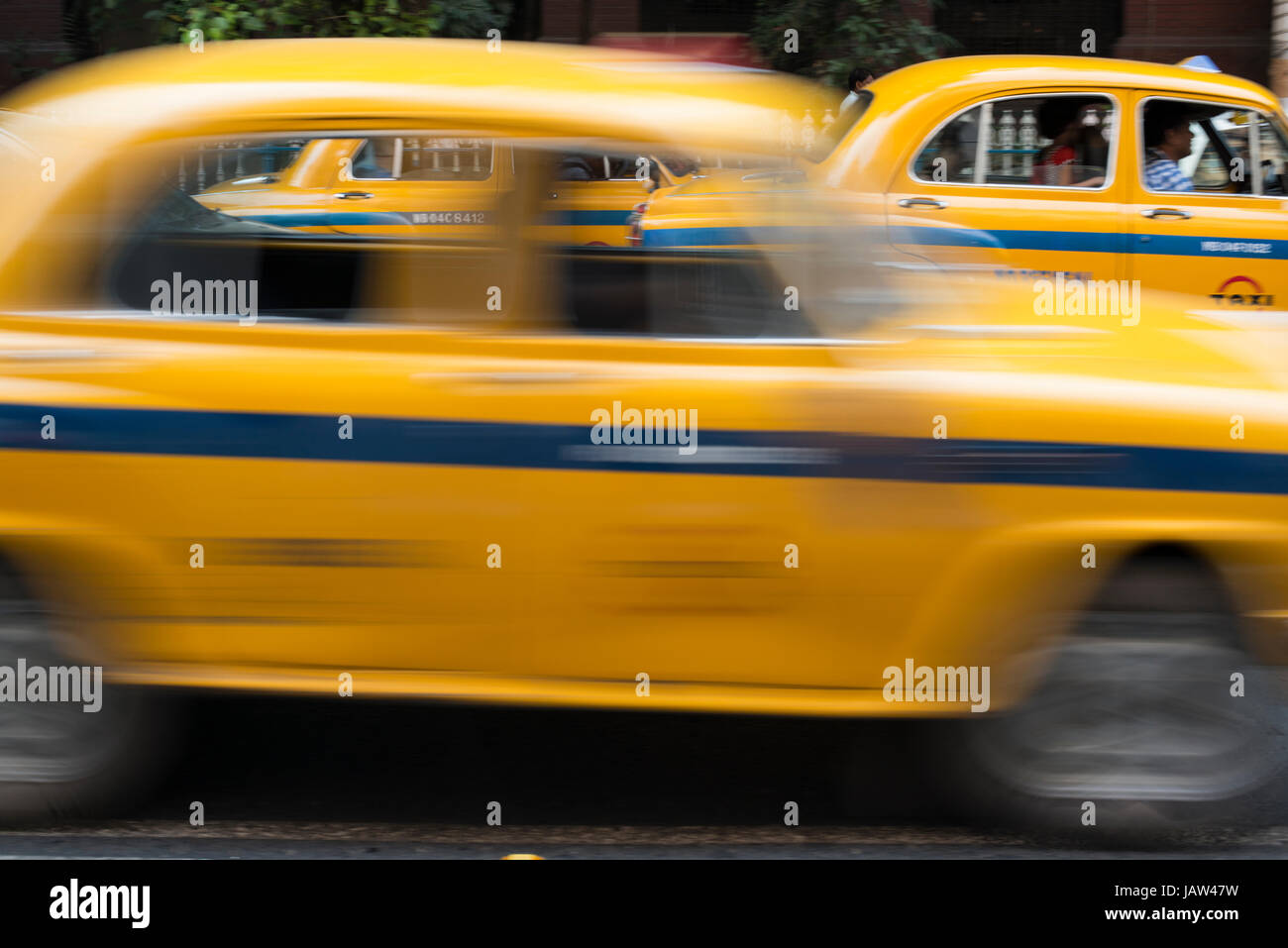 An iconic yellow taxi drives down a road in Kolkata (Calcutta), West Bengal, India India Stock Photo