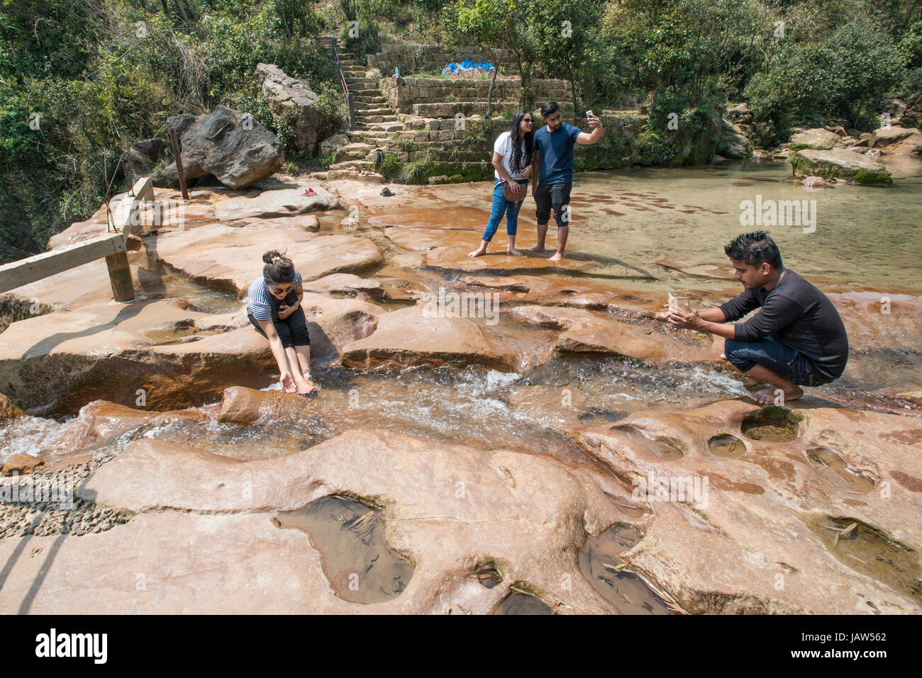 A group of tourists enjoy the water above Wahkaba Falls in Meghalaya state, India Stock Photo