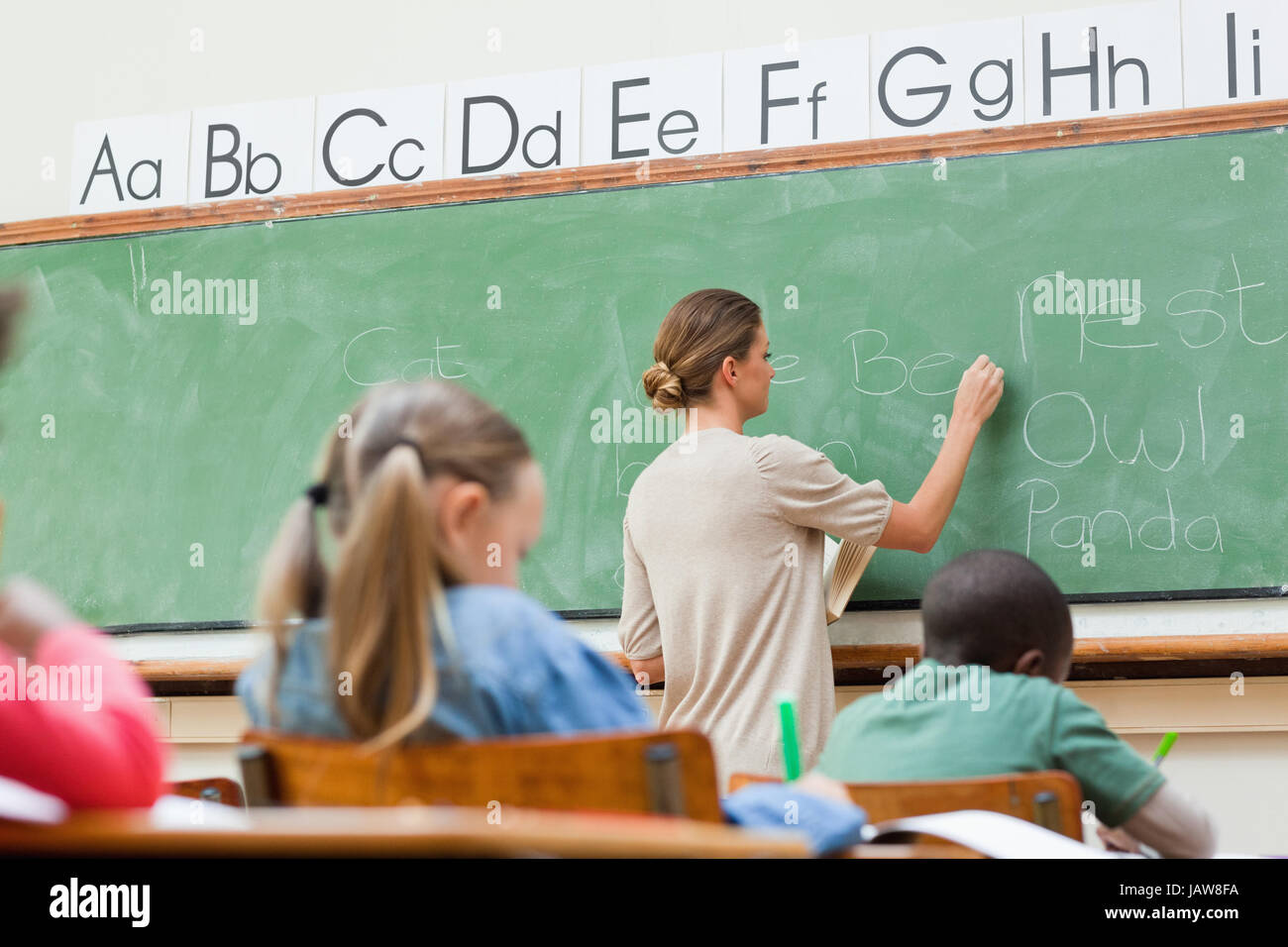 Elementary teacher writing on board Stock Photo Alamy