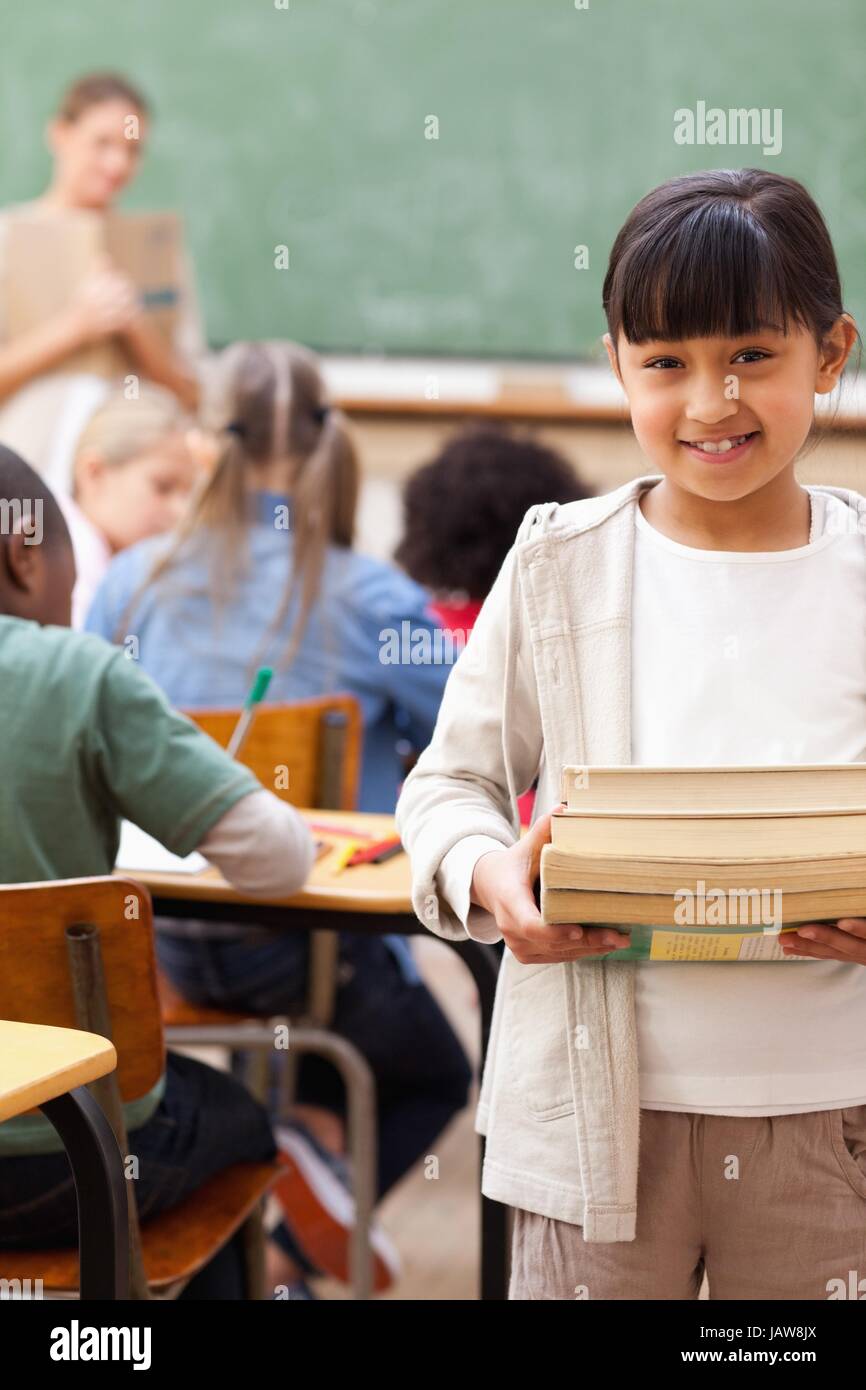 Smiling student standing with pile of books Stock Photo - Alamy
