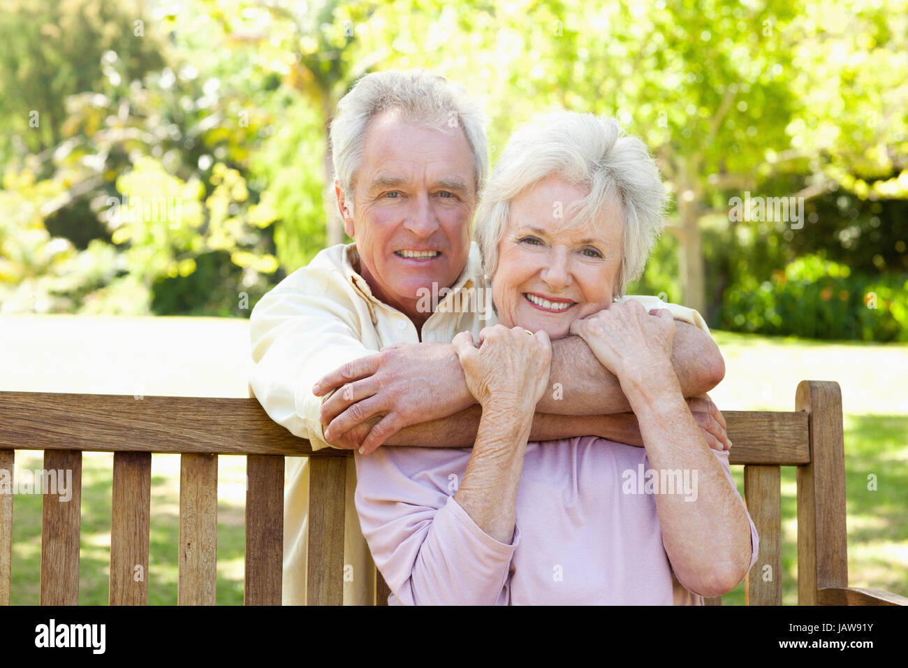 Man smiling as he holds his friend from behind a bench Stock Photo - Alamy