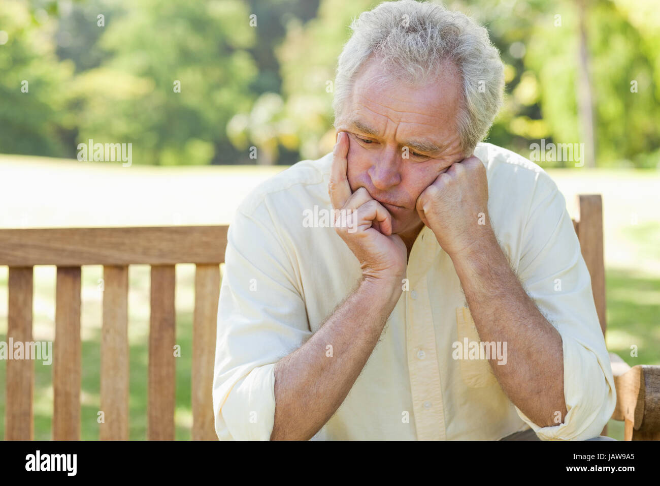 Man holding his face between his hands as he sits on a bench Stock ...