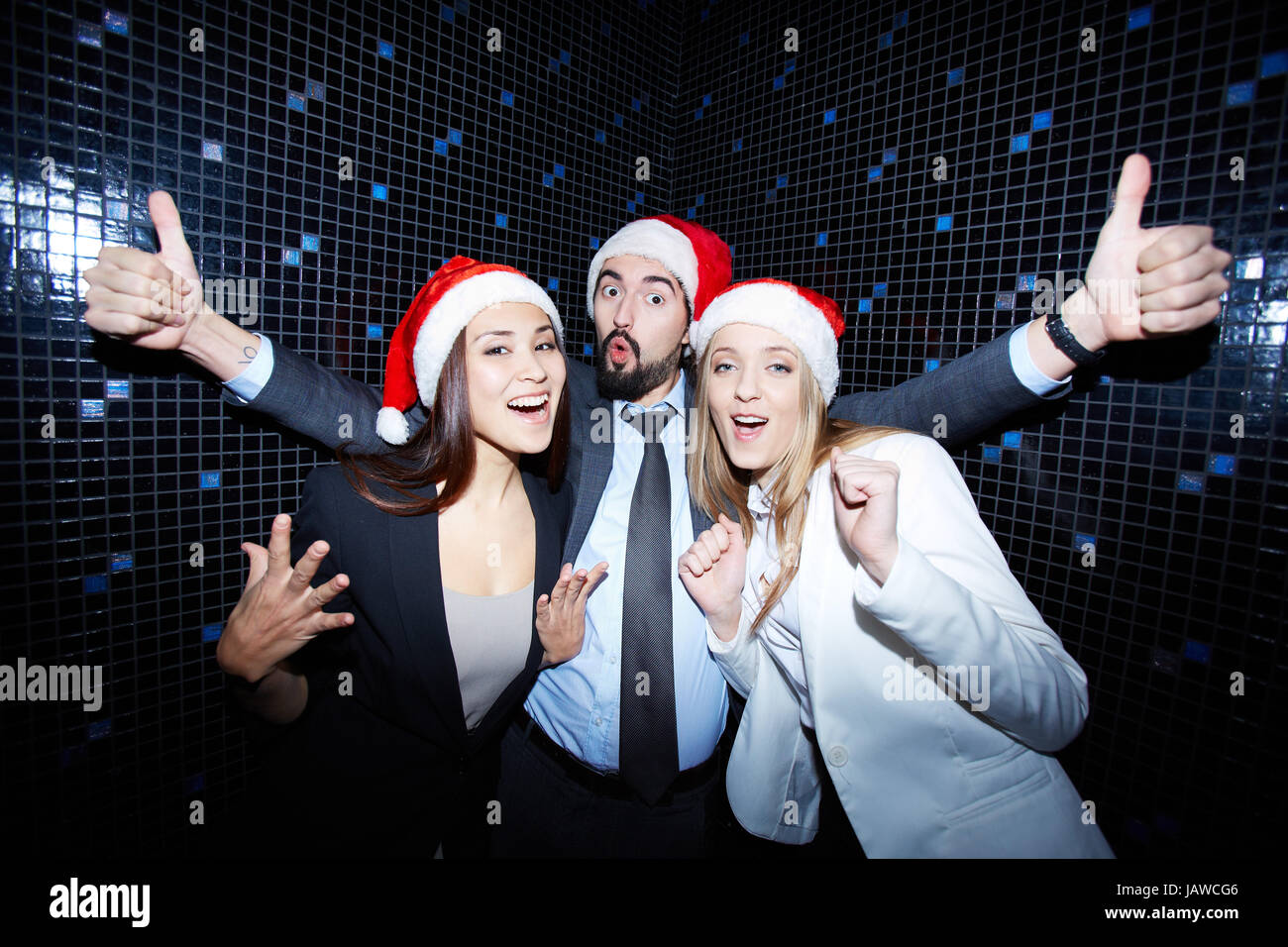 Portrait of joyful colleagues in Santa caps having fun in nightclub ...