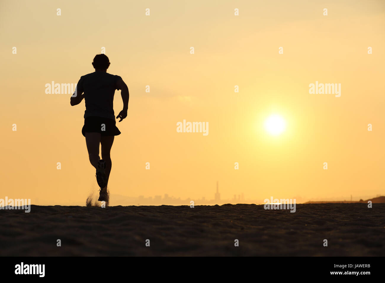 Back view of a man running on the beach at sunset with the horizon in ...