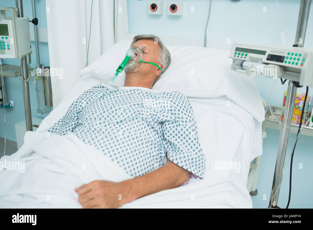 Unconscious patient on a bed with an oxygen mask in a hospital Stock