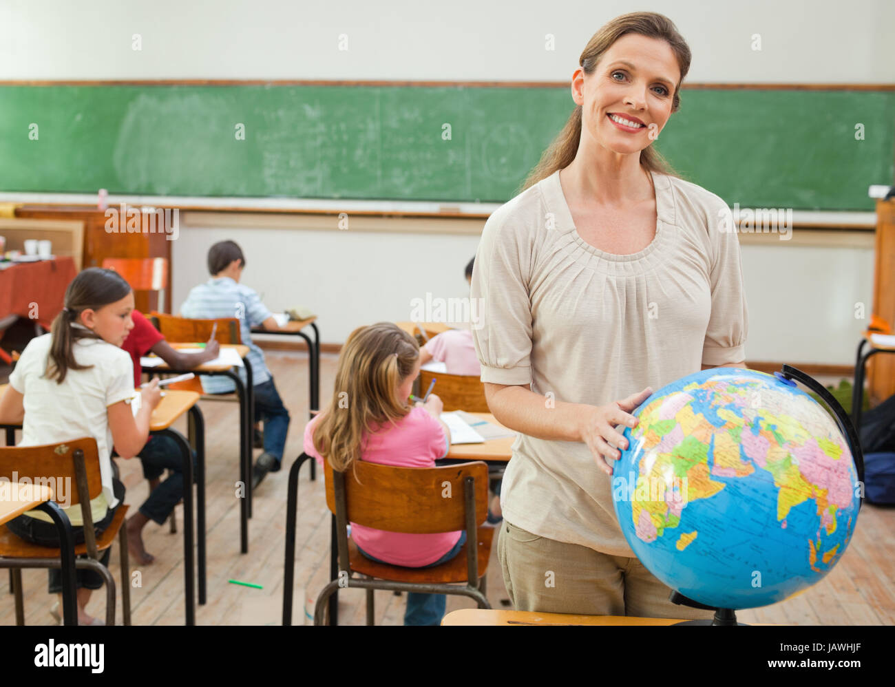 Smiling teacher holding globe Stock Photo - Alamy