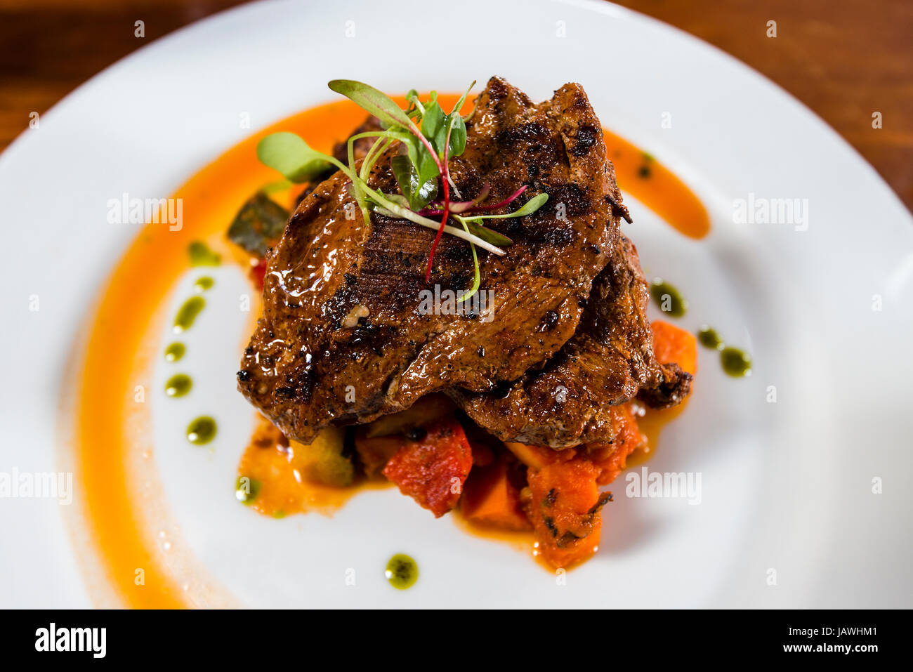 A gourmet chef prepared meal of roasted alpaca and peppers. Stock Photo