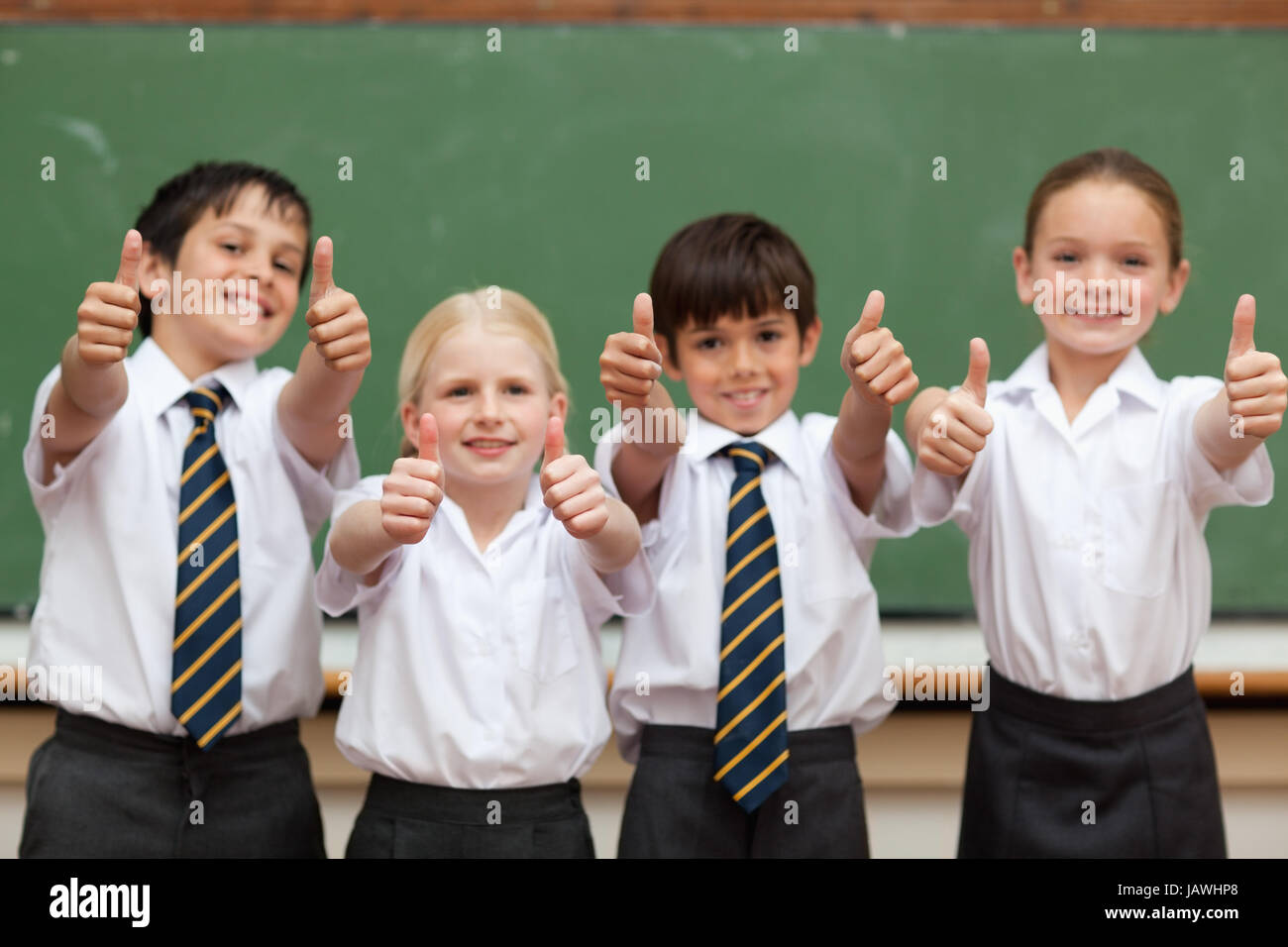 Smiling students in school uniforms giving thumbs up Stock Photo - Alamy
