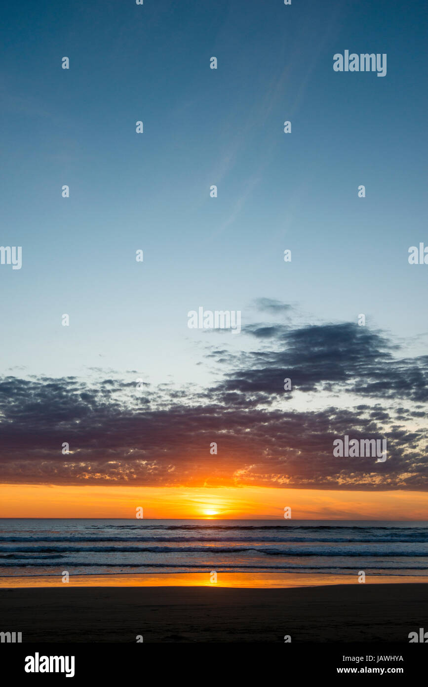 Sunset sinks into a broad horizon over the southern ocean. Stock Photo