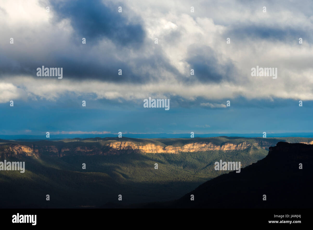 A late afternoon storm descends over a sandstone plateau and eucalyptus forest valley. Stock Photo
