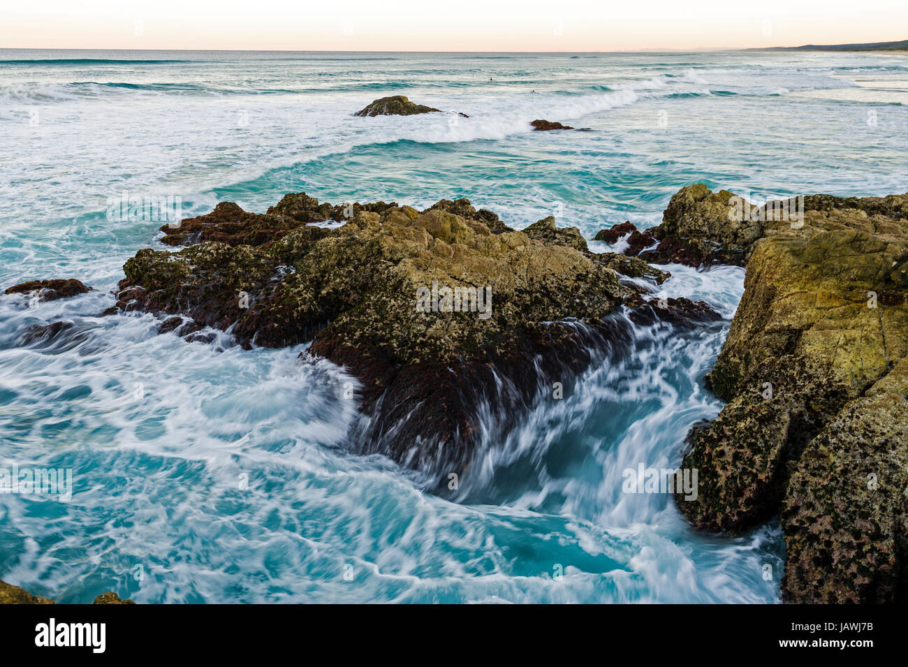 Waves smash against jagged rocks on a pristine coastline. Stock Photo